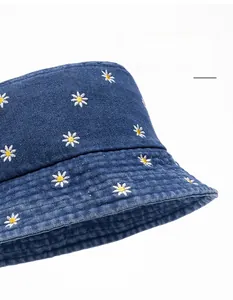 Detail of embroidered daisy patterns and widened brim on dark blue denim bucket hat