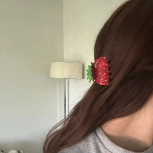 Sweet red acrylic strawberry hair claw clip worn in a low ponytail style on a model
