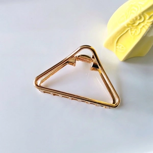Detailed close-up of a hollow geometric gold triangle metal hair claw clip for women