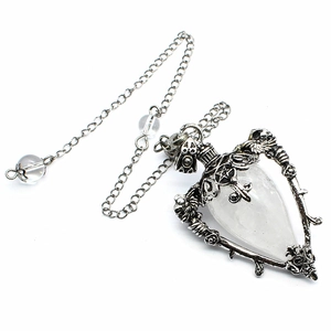 Macro shot of silver pendulum necklace featuring a pentagram, rose patterns and crystal bead