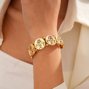 Détails des pendentifs croix et ichthys sur un bracelet à maillons bicolore de style chic