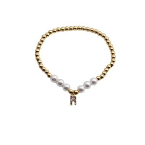 Detail of beaded bracelet with gold copper beads, white pearls and a colorful letter R charm