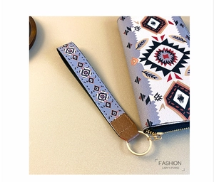 Detail of ethnic geometric pattern long wallet with gold hardware and wrist strap