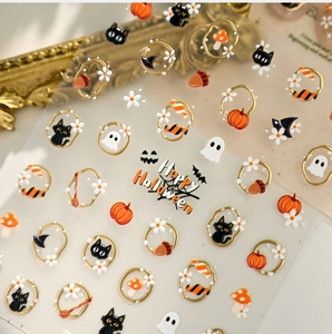 Macro detail of 3D Halloween nail stickers featuring gold pumpkin and black cat designs