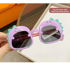 Close-up of purple dinosaur frames with green spikes and dark grey lenses for kids