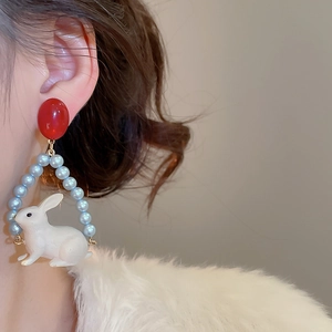Vue détaillée d'une boucle d'oreille lapin avec perles bleues et clou rouge