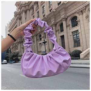 Minimalist purple ruched cloud bag with single handle shown in outdoor street setting