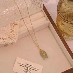 Makro-Detail des Fisch-Natursteinanhängers mit rosa Edelsteinen und Goldkette