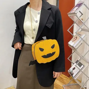 Detail of pumpkin crossbody bag with bat charm and gold chain strap on black blazer