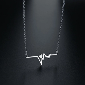 Silver heartbeat waveform necklace with heart accent on a textured black background