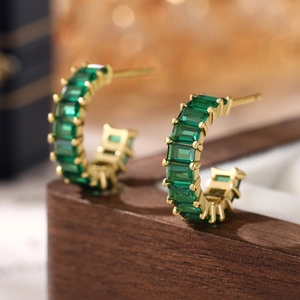 Macro view of gold-plated 925 silver hoop earrings with emerald green square zircon stones