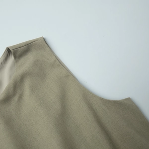 Macro detail of olive green linen vest showing fine fabric texture and shoulder stitching