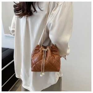 Detail of brown quilted bucket bag with gold chain strap and pearl drawstring charms