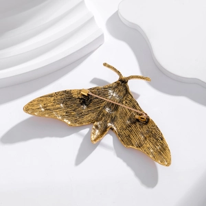 Vintage golden moth brooch with antique metal texture shown from the back perspective