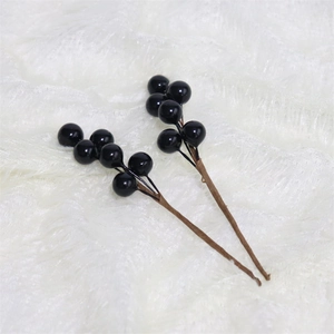 Close-up of two glossy black decorative berries on a soft white faux fur background