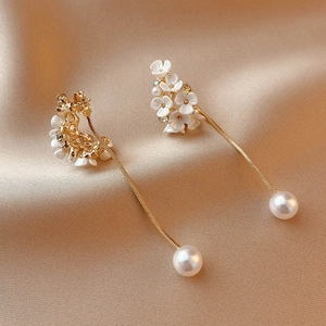 Dettaglio di orecchini a fiore con nappe, petali bianchi, strass e perle grandi