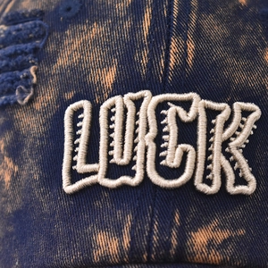 Vintage navy blue washed denim baseball cap with LUCK embroidery and distressed details