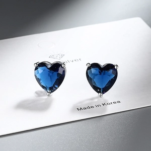 Macro shot of heart-shaped earrings with deep blue zircons set in silver claws