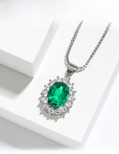 Detail of emerald green oval pendant surrounded by sparkling white zircon stones