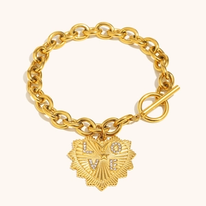 Close-up of gold chain bracelet with love heart pendant and sparkling gemstones
