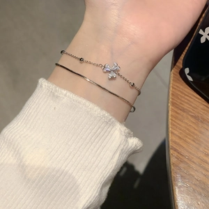 Detail shot of double-layered silver bracelet with zircon flower charm and snake chain