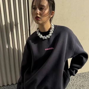 Close-up of pink 'maskin.' letter print on dark grey oversized crewneck sweatshirt
