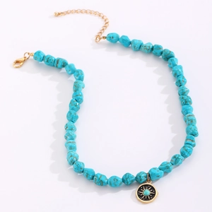 Detail of bohemian turquoise beaded necklace with gold lobster clasp and sun pendant