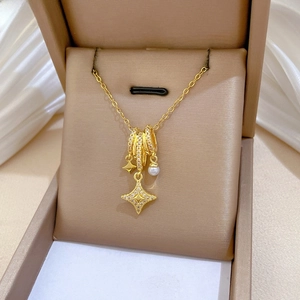 Close-up of gold star necklace with shimmering crystals and white pearl in a gift box