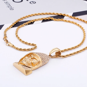 Detail of a golden skull pendant with sparkling rhinestones on a twist chain necklace