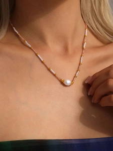 Dettaglio della collana di perle con grande perla barocca e delicati accenti dorati