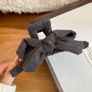 Close-up of charcoal grey fabric bow hair claw clip with detailed knit texture