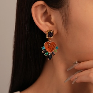 Close-up of vintage heart earrings with purple gemstone and multicolored crystals on model