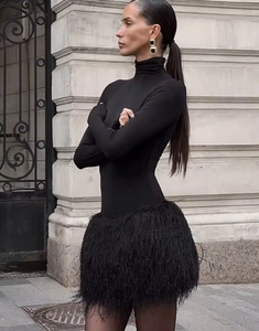 Dettaglio di un elegante abito nero aderente con texture di frange in piume raffinate