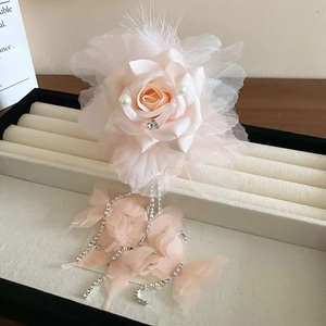 Détail d'une pince à cheveux rose avec rose en satin, perles et glands en cristal