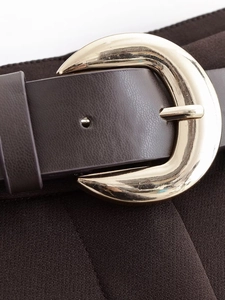 Close-up of a vintage brown leather belt with a circular golden metal buckle detail