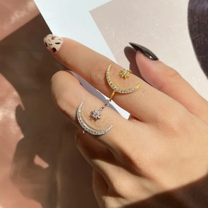 Detail of adjustable star and moon open rings in gold and silver with zircon accents