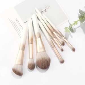Set of 7 soft fiber makeup brushes with white to gold gradient glitter handles on white background