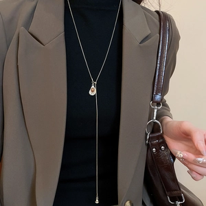 Detail of tiger eye heart pendant on a gold long chain worn with a formal blazer