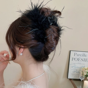 Detailed view of an elegant black acrylic hair claw clip with feather accents on a model