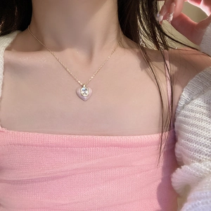 Close-up of pink enamel heart pendant with square zircon on golden necklace chain