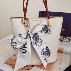 Detail of camellia silk scarf bow on cream bucket bag with brown handles