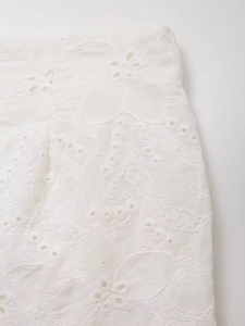 Detail of white embroidered hollow-out fabric with intricate floral patterns for blazer