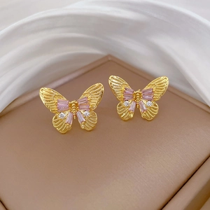 Detail of butterfly earrings with pink zircon stones on premium silk background