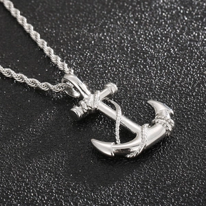 Macro shot of silver anchor pendant with rope details on a black matte surface