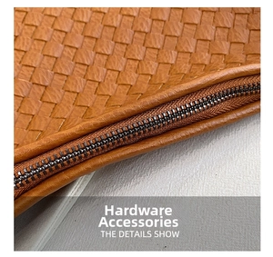 Close-up of metal zipper and fine stitching on a brown woven texture leather handbag