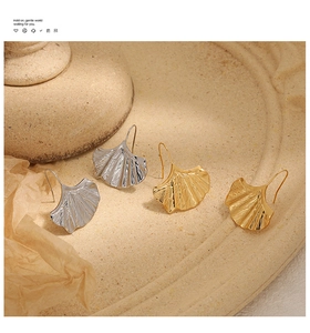 Vue détaillée des boucles d'oreilles feuille de ginkgo en argent et or sur une pierre