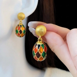 Vintage gold oval earrings with colorful enamel lattice pattern shown on a hand