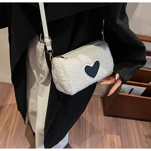 Détail du sac cylindre en peluche blanche avec patch cœur noir et boucle dorée