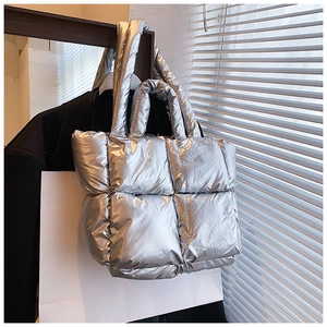 Detailed view of silver quilted padded tote bag with metallic finish hanging on a rack