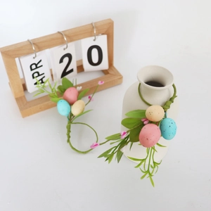 Close-up of Easter egg napkin ring with colorful speckled eggs and faux greenery